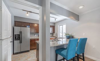 A kitchen with a refrigerator, sink, and blue chairs